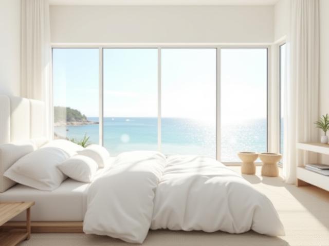 Bright modern coastal bedroom with large windows and soft white furnishings